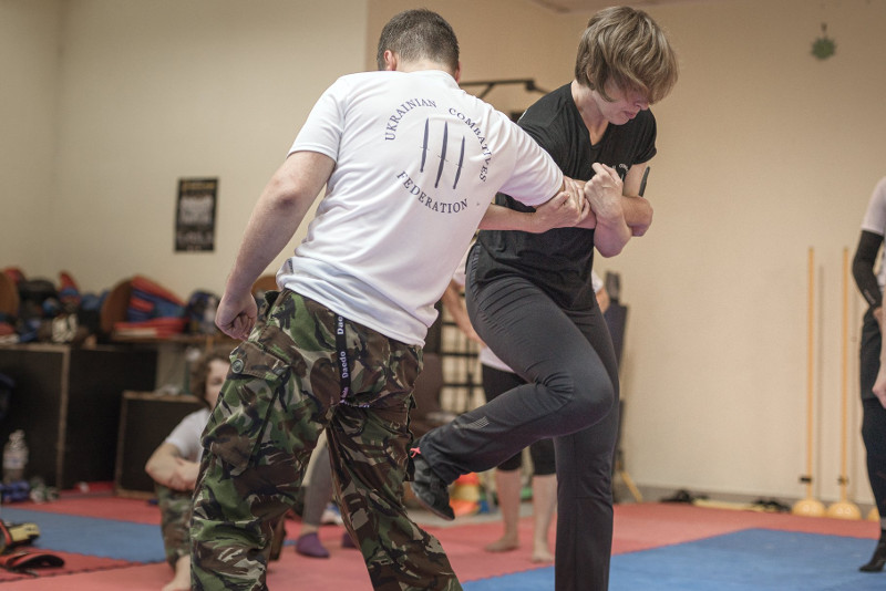 krav maga instructor demonstrates kick to the knee against opponent with a knife